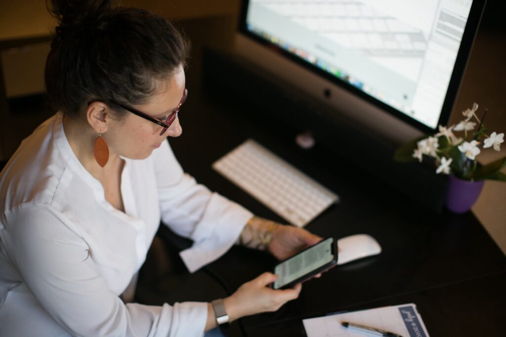 Catherine Pearce working at her desk, checking her phone